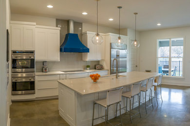 Example of a large minimalist concrete floor and gray floor eat-in kitchen design in Other with an undermount sink, shaker cabinets, white cabinets, quartz countertops, white backsplash, glass tile backsplash, stainless steel appliances, an island and white countertops