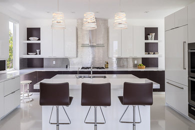Large trendy l-shaped porcelain tile enclosed kitchen photo in Miami with a drop-in sink, flat-panel cabinets, white cabinets, concrete countertops, metallic backsplash, metal backsplash, stainless steel appliances and an island