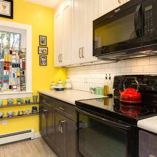 This is an example of a small midcentury galley eat-in kitchen in Providence with a drop-in sink, flat-panel cabinets, white cabinets, laminate benchtops, white splashback, subway tile splashback, black appliances, vinyl floors, no island and grey floor.