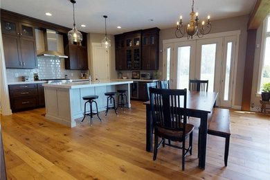 Inspiration for a transitional light wood floor eat-in kitchen remodel in Indianapolis with an undermount sink, flat-panel cabinets, medium tone wood cabinets, quartz countertops, white backsplash, subway tile backsplash, stainless steel appliances and an island