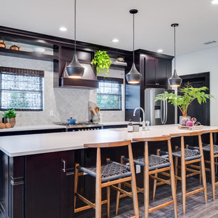 This is an example of a mid-sized tropical single-wall eat-in kitchen in Orange County with an undermount sink, shaker cabinets, dark wood cabinets, laminate benchtops, grey splashback, ceramic splashback, stainless steel appliances, medium hardwood floors and with island.