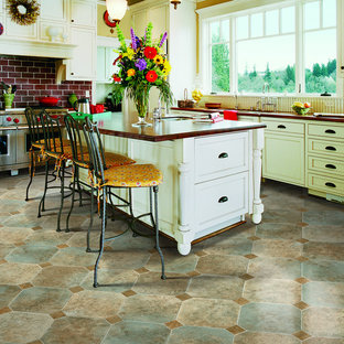 Photo of a mid-sized country l-shaped eat-in kitchen in Other with a double-bowl sink, shaker cabinets, white cabinets, wood benchtops, white splashback, timber splashback, stainless steel appliances, ceramic floors, with island and beige floor.