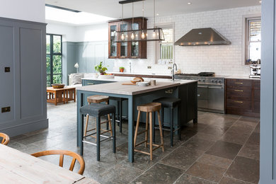 Photo of a medium sized traditional single-wall kitchen/diner in London with flat-panel cabinets, white splashback, metro tiled splashback, a breakfast bar and grey floors.