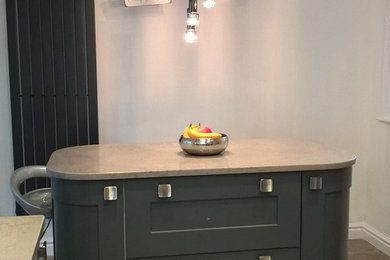 Cette photo montre une cuisine tendance avec un placard à porte shaker, des portes de placard grises, un plan de travail en quartz, un électroménager en acier inoxydable et îlot.