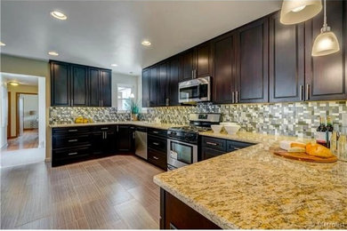 Large trendy u-shaped porcelain tile eat-in kitchen photo in Denver with an undermount sink, raised-panel cabinets, dark wood cabinets, granite countertops, multicolored backsplash, mosaic tile backsplash, stainless steel appliances and a peninsula