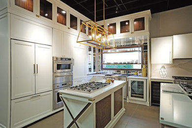 Small transitional eat-in kitchen photo in Miami with recessed-panel cabinets, white cabinets, quartz countertops, metallic backsplash, mirror backsplash, paneled appliances and an island
