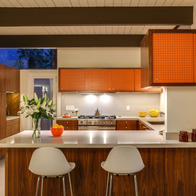 1960s u-shaped concrete floor, beige floor, exposed beam and shiplap ceiling eat-in kitchen photo in Other with an undermount sink, flat-panel cabinets, medium tone wood cabinets, quartz countertops, white backsplash, stainless steel appliances, a peninsula and beige countertops