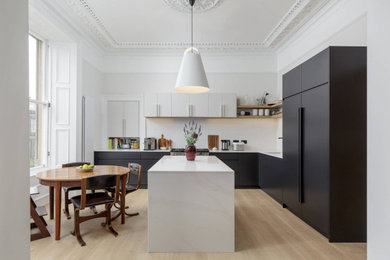 Источник вдохновения для домашнего уюта: кухня в современном стиле с обеденным столом, черными фасадами, столешницей из кварцита, белым фартуком, полом из ламината, островом и белой столешницей