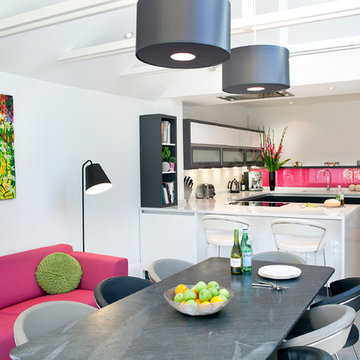 Monochrome kitchen diner with colourful artwork, sofa and bright pink glass