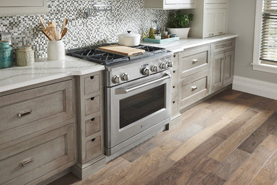 Foto de cocinas en L clásica renovada de tamaño medio abierta con electrodomésticos de acero inoxidable, suelo de madera clara y suelo marrón