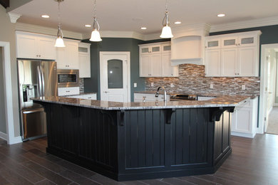 Open concept kitchen - craftsman medium tone wood floor open concept kitchen idea in Other with recessed-panel cabinets, white cabinets, granite countertops, multicolored backsplash, glass tile backsplash, stainless steel appliances and an island