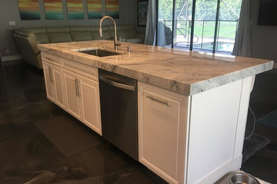 Mid-sized minimalist single-wall concrete floor and gray floor eat-in kitchen photo in Miami with an undermount sink, quartzite countertops, white backsplash, stainless steel appliances and an island