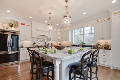 Example of a large classic l-shaped medium tone wood floor eat-in kitchen design in Philadelphia with a farmhouse sink, beaded inset cabinets, white cabinets, quartzite countertops, white backsplash, stone tile backsplash, black appliances and an island