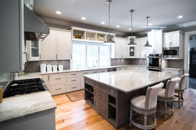 Huge transitional u-shaped medium tone wood floor and beige floor kitchen pantry photo in Other with an undermount sink, raised-panel cabinets, quartzite countertops, ceramic backsplash, an island, white cabinets, gray backsplash and stainless steel appliances