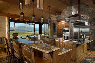 Large mountain style u-shaped medium tone wood floor and brown floor eat-in kitchen photo in Other with an undermount sink, raised-panel cabinets, medium tone wood cabinets, stainless steel appliances, granite countertops, an island, multicolored backsplash and stone tile backsplash