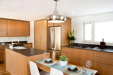 Example of a trendy l-shaped eat-in kitchen design in Denver with an undermount sink, flat-panel cabinets, light wood cabinets, quartz countertops, white backsplash, glass tile backsplash and stainless steel appliances