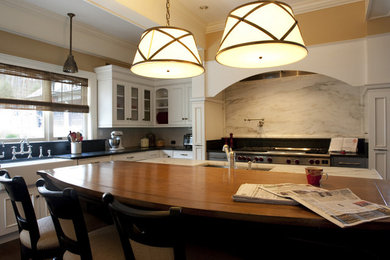 Large elegant u-shaped dark wood floor eat-in kitchen photo in New York with a farmhouse sink, recessed-panel cabinets, white cabinets, soapstone countertops, gray backsplash, ceramic backsplash, stainless steel appliances and an island