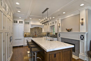 Example of a mid-sized classic u-shaped dark wood floor eat-in kitchen design in Newark with a farmhouse sink, shaker cabinets, white cabinets, marble countertops, multicolored backsplash, mosaic tile backsplash, paneled appliances and an island