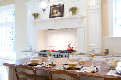 Klassische Küche in L-Form mit Landhausspüle, Kassettenfronten, weißen Schränken und Elektrogeräten mit Frontblende in New York