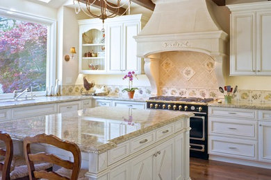 Inspiration for a large timeless u-shaped medium tone wood floor enclosed kitchen remodel in San Francisco with recessed-panel cabinets, white cabinets, granite countertops, beige backsplash, ceramic backsplash, an island, an undermount sink and black appliances