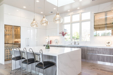 Inspiration for a large modern u-shaped light wood floor and brown floor open concept kitchen remodel in San Francisco with an undermount sink, flat-panel cabinets, white cabinets, quartz countertops, white backsplash, stone slab backsplash, stainless steel appliances and an island