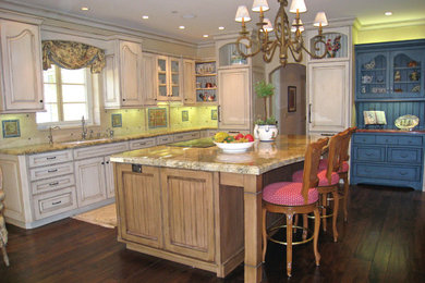Example of a mid-sized country l-shaped dark wood floor and brown floor eat-in kitchen design in Santa Barbara with an undermount sink, raised-panel cabinets, distressed cabinets, granite countertops, multicolored backsplash, ceramic backsplash, paneled appliances and an island