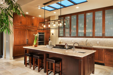 Example of a tuscan kitchen design in Santa Barbara with an undermount sink, glass-front cabinets, medium tone wood cabinets, beige backsplash and paneled appliances