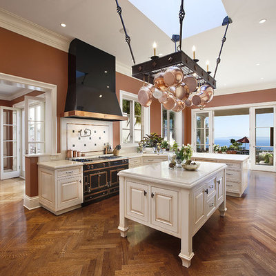Kitchen - large mediterranean medium tone wood floor kitchen idea in Santa Barbara with raised-panel cabinets, marble countertops, white cabinets, black appliances and an island