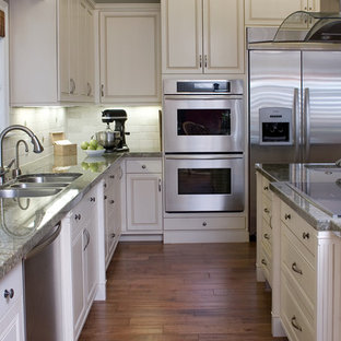 Photo of a traditional kitchen in Los Angeles with stainless steel appliances, a triple-bowl sink, raised-panel cabinets, white cabinets, white splashback and granite benchtops.