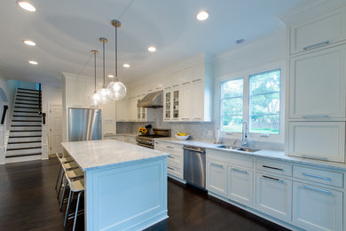 Example of a mid-sized classic l-shaped dark wood floor enclosed kitchen design in Charlotte with an undermount sink, shaker cabinets, white cabinets, marble countertops, white backsplash, stone slab backsplash, stainless steel appliances and an island