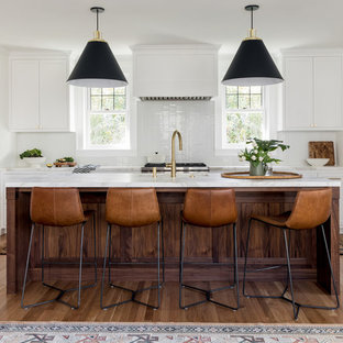 Transitional kitchen pictures - Transitional l-shaped medium tone wood floor and brown floor kitchen photo in Portland with an undermount sink, recessed-panel cabinets, white cabinets, white backsplash, stainless steel appliances, an island and white countertops
