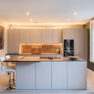 Inspiration for a medium sized contemporary galley kitchen in Gloucestershire with flat-panel cabinets, grey cabinets, metallic splashback, black appliances, an island and white floors.