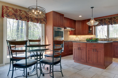 Eat-in kitchen - mid-sized traditional u-shaped travertine floor and beige floor eat-in kitchen idea in New York with granite countertops, stainless steel appliances, a farmhouse sink, shaker cabinets, medium tone wood cabinets, beige backsplash, subway tile backsplash and an island