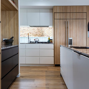Photo of a contemporary u-shaped kitchen in Sunshine Coast with an undermount sink, flat-panel cabinets, white cabinets, window splashback, panelled appliances, medium hardwood floors, with island, brown floor and grey benchtop.