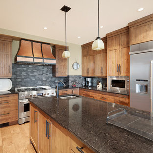 Huge rustic kitchen ideas - Huge mountain style u-shaped light wood floor kitchen photo in Vancouver with a double-bowl sink, beaded inset cabinets, medium tone wood cabinets, granite countertops, gray backsplash, slate backsplash, stainless steel appliances, an island and black countertops