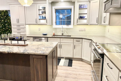 This is an example of a medium sized classic l-shaped kitchen/diner in Other with a submerged sink, flat-panel cabinets, grey cabinets, engineered stone countertops, white splashback, metro tiled splashback, stainless steel appliances, vinyl flooring, an island, brown floors and grey worktops.