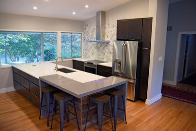 Mid-sized trendy single-wall medium tone wood floor and brown floor open concept kitchen photo in DC Metro with an undermount sink, flat-panel cabinets, dark wood cabinets, quartz countertops, gray backsplash, stone tile backsplash, stainless steel appliances and an island