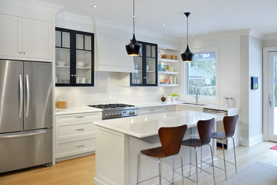 Kitchen - mid-sized traditional l-shaped light wood floor kitchen idea in Toronto with an undermount sink, recessed-panel cabinets, quartz countertops, white backsplash, porcelain backsplash, stainless steel appliances and an island