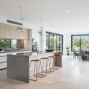 Contemporary galley kitchen in Sydney with an undermount sink, flat-panel cabinets, white cabinets, light hardwood floors, with island, beige floor and grey benchtop.