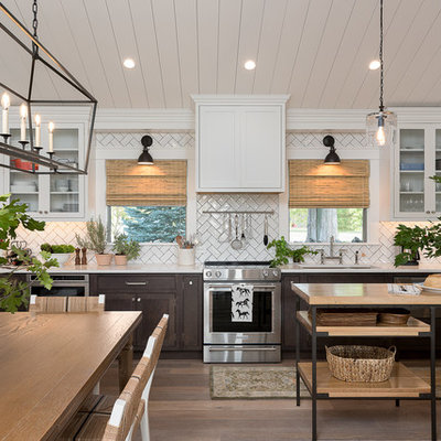 Example of a mid-sized cottage single-wall brown floor and medium tone wood floor open concept kitchen design in Other with an undermount sink, white cabinets, quartz countertops, white backsplash, subway tile backsplash, stainless steel appliances, an island and shaker cabinets