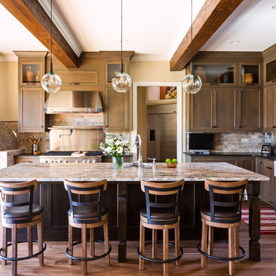 Inspiration for a rustic l-shaped medium tone wood floor and brown floor kitchen remodel in Charlotte with a farmhouse sink, granite countertops, multicolored backsplash, stone tile backsplash, stainless steel appliances, an island, black countertops, shaker cabinets and dark wood cabinets