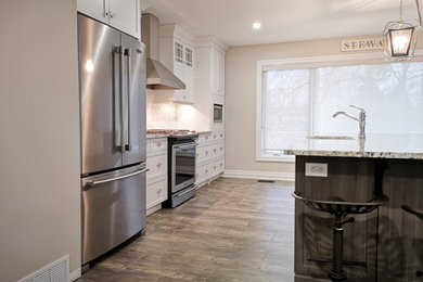 Example of a mid-sized country single-wall vinyl floor and brown floor eat-in kitchen design in Other with shaker cabinets, white cabinets, quartz countertops, white backsplash, ceramic backsplash, stainless steel appliances, an island, multicolored countertops and an undermount sink
