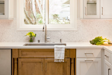 Example of a mid-sized classic l-shaped eat-in kitchen design in San Francisco with an undermount sink, shaker cabinets, white cabinets, white backsplash, stainless steel appliances and no island