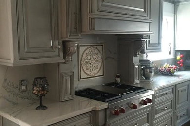 ヒューストンにある中くらいなトラディショナルスタイルのおしゃれなキッチン (レイズドパネル扉のキャビネット、グレーのキャビネット、大理石カウンター、シルバーの調理設備、無垢フローリング) の写真