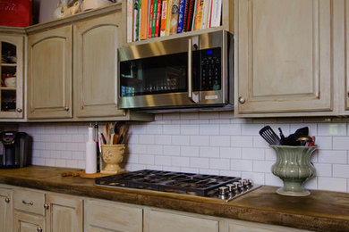 Kitchen - mid-sized traditional u-shaped medium tone wood floor kitchen idea in Other with a farmhouse sink, distressed cabinets, concrete countertops, white backsplash, subway tile backsplash, stainless steel appliances, an island and raised-panel cabinets