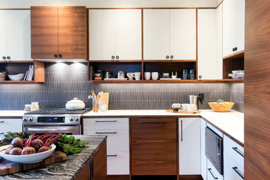 Cette image montre une cuisine design avec un placard à porte plane, un plan de travail en granite, une crédence noire, une crédence en céramique, un électroménager en acier inoxydable et parquet foncé.