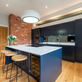 Offene, Einzeilige, Große Klassische Küche mit integriertem Waschbecken, Schrankfronten im Shaker-Stil, blauen Schränken, Quarzit-Arbeitsplatte, Küchenrückwand in Schwarz, Rückwand aus Spiegelfliesen, Küchengeräten aus Edelstahl, hellem Holzboden, Kücheninsel, orangem Boden und weißer Arbeitsplatte in Edinburgh