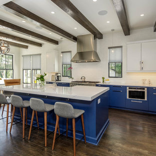 Contemporary kitchen inspiration - Inspiration for a contemporary dark wood floor and brown floor kitchen remodel in Atlanta with flat-panel cabinets, blue cabinets, solid surface countertops, white backsplash, stainless steel appliances, an island, white countertops and subway tile backsplash