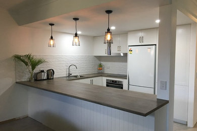 Inspiration for a small traditional u-shaped open plan kitchen in Brisbane with a built-in sink, shaker cabinets, white cabinets, laminate countertops, white splashback, metro tiled splashback, stainless steel appliances, ceramic flooring, a breakfast bar and grey floors.