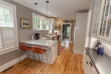 Eat-in kitchen - galley medium tone wood floor eat-in kitchen idea in Atlanta with an undermount sink, shaker cabinets, white cabinets, quartz countertops, gray backsplash, porcelain backsplash, stainless steel appliances and white countertops
